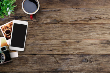 Office table with mobile phone, photos and coffee cup. View from above with copy space flat lay or hero header concept.