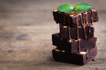 Piece of stack homemade dark chocolate brownies topping with almonds slices and mint on wood...
