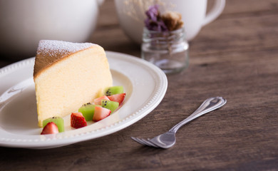 Homemade Japanese cheesecake so delicious, fluffy,lite and soft sparkling with  icing, fresh fruit:kiwi and strawberry. Soft cheesecake Japanese style. Souffle cotton cheesecake put on rustic wood.