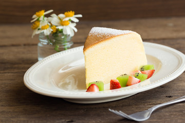 Homemade Japanese cheesecake so delicious, fluffy,lite and soft sparkling with  icing, fresh fruit:kiwi and strawberry. Soft cheesecake Japanese style. Souffle cotton cheesecake put on rustic wood.