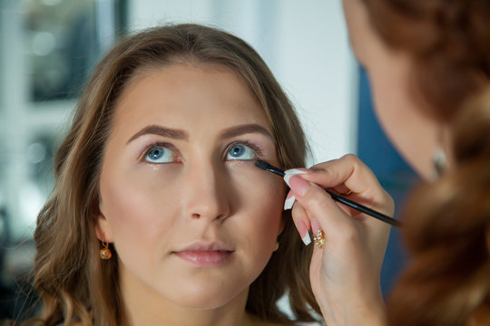 Make up artist doing professional makeup of young woman