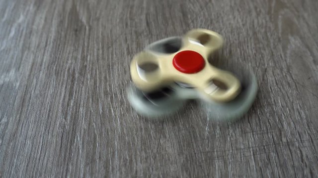 two white hand spinner spinning on grey background or fidget spinners.