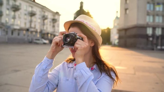 Girl is walking around the city and taking photos of sights on a film camera