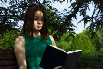 Fototapeta premium Young pretty girl reads a book, outdoor 