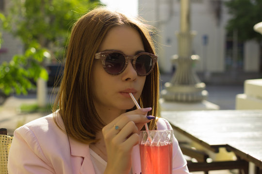 Young pretty girl drinks a cold beverage, outdoor  