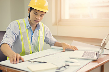 Engineer man working with laptop and blueprints sketching a construction project .Business concept with vintage color.