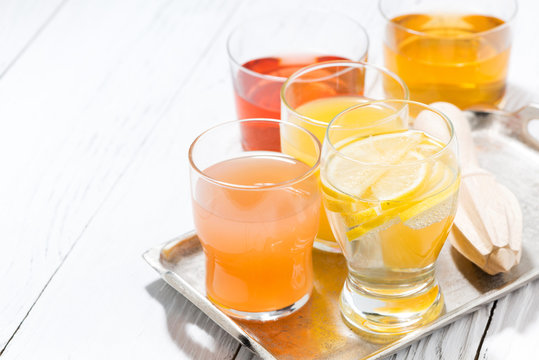 assortment of fresh citrus juices in glasses and white background