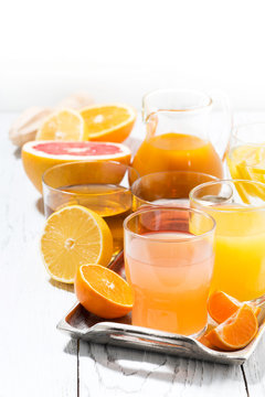 assortment of fresh citrus juices on white table, vertical