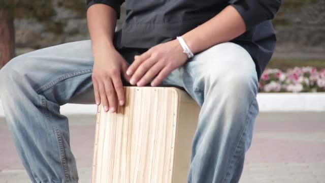A street drummer musician plays a percussion instrument Cajon.