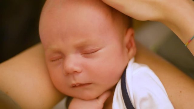adorable little newborn baby is falls asleep in mother's arms. Close up shot