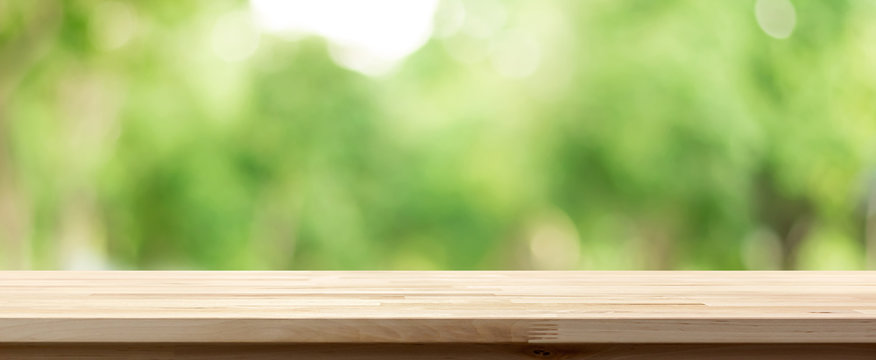 Wood table top on blur green background of trees in the park, panoramic banner