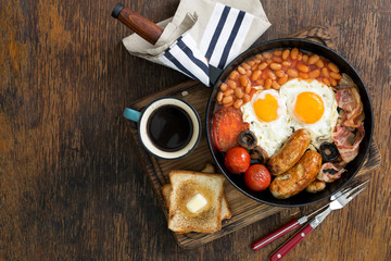 Full English breakfast on wooden table with copy space
