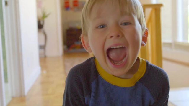 Portrait of adorable little boy making faces at the camera in slow motion in his hallway in his home