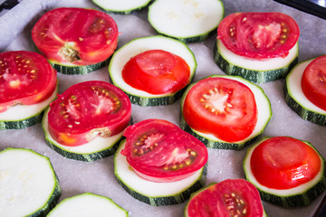 Sliced tomatoes stacked on slices of zucchini. Vegetables prepared for roasting. Selective focus.