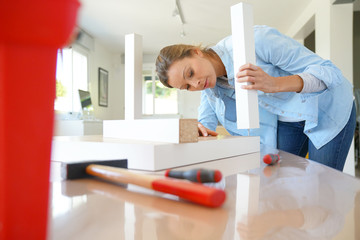 Woman doing DIY work, assembling furniture at home