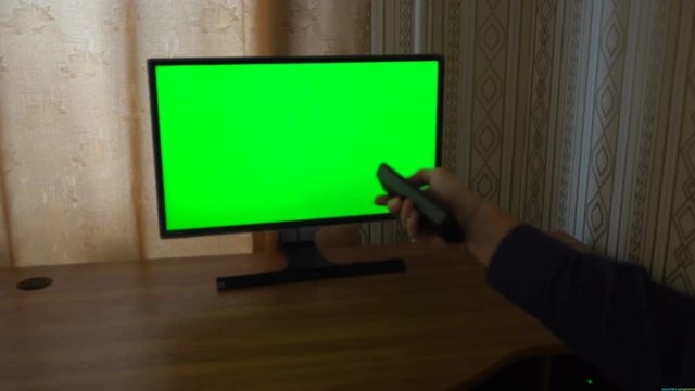 Male Hand With TV Remote Switching Channels On A Green Screen TV Point Of View.