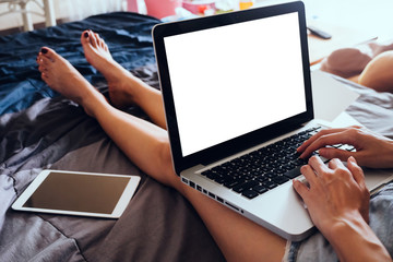 Close up of young woman using laptop while sitting on her bed,  Films grain filter.