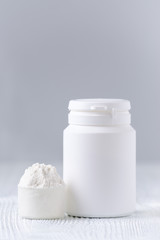 a spoon with white powder and a bottle on gray, selective focus