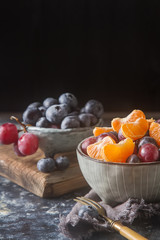 Plate with fruit salad of mandarin, grape, blueberry. Delicious and hearty breakfast options. Dark background.