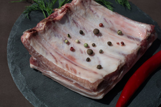 Raw lamb ribs with chili pepper, spices, dill on shale tray close up - meat for picnic
