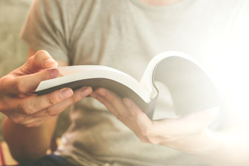 Close up of male hands holding a book to read, Flare from the sunlight