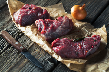 Meat with spices and vegetables on wooden background. Knife. food