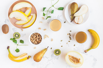 Fresh smoothie with pear, banana, melon, kiwi. Summer fruit cocktail on white table. Vegan, vegetarian, detox, dieting concept. Flat lay, top view