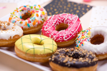 Party. Different colourful sugary round glazed donuts and bottles of drinks on light color background.
