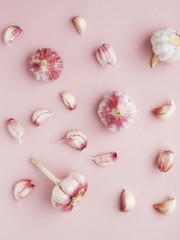 Young pink garlic on a pink paper textured background. Pattern of garlic. Food background. Top view.