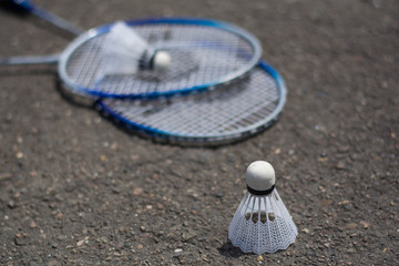 Plastic shuttlecock on badminton, blue rackets background