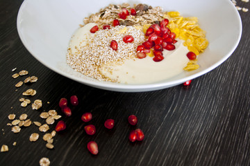Teller mit Müsli, Cornflakes, Joghurt und Granatapfelkernen