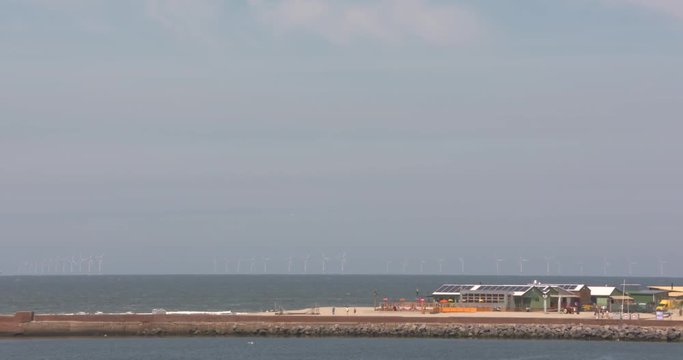 Offshore windpark at the North Sea coast. Beach pavilions in front.IJMUIDEN, THE NETHERLANDS - MAY 2017