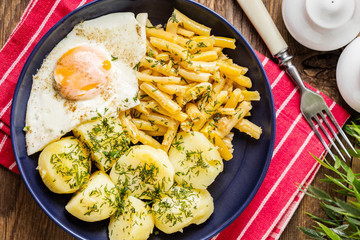Fried egg served with potatoes and yellow beans.