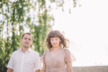 Obraz premium beautiful couple on a walk, the girl in the beige dress and the guy wearing light clothing in the Park, summer, nature, love story, family, values
