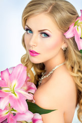 Obraz na płótnie Canvas Beautiful woman portrait with flowers on head and in hands. Young lady posing on white background. Gorgeous make up. Magnetic view. Glamour lipstick.