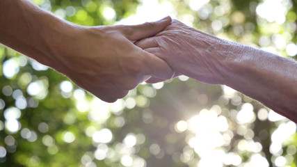 The hand of a young girl (woman) holds the hand of an elderly person, a sign of love, help, faith...