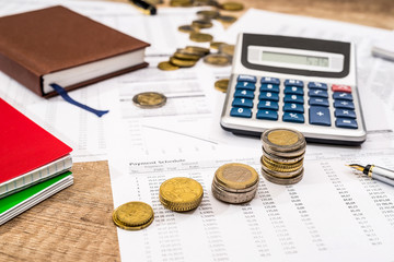 notepad, financial documents, calculator, pen and coin