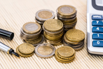 Euro coin with pen and calculator. close up.