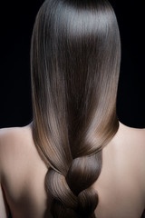 female hairstyle. Dark long pigtail. Shine hair, hair care