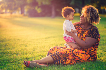 African american mother with her mixed race daughter laughing in the park, enjoying a beautiful day outside - 159277663