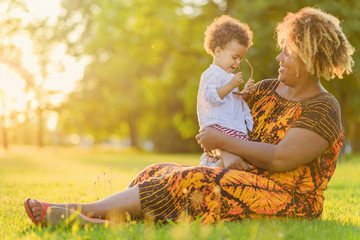 African american mother with her mixed race daughter laughing in the park, enjoying a beautiful day...