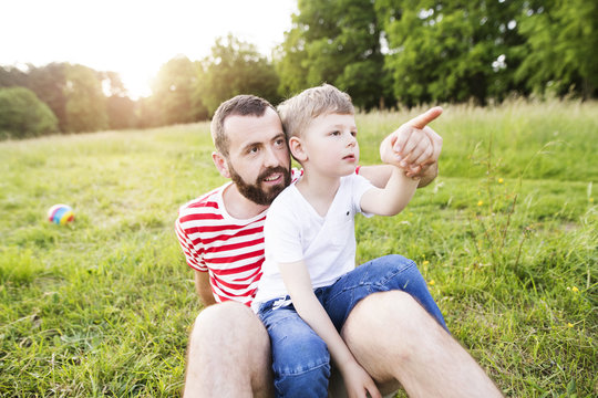 Hipster father and little son on green meadow. Sunny summer day.