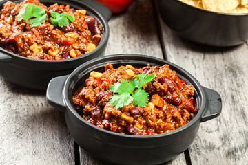 Bowls of hot chili con carne with ground beef, beans, tomatoes and corn