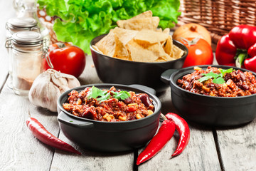 Bowls of hot chili con carne with ground beef, beans, tomatoes and corn