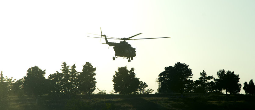 silhouette of military helicopter over the trees at sunset. vintage colored picture