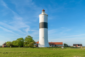 The tall lighthouse Long Jan on the island Oland in Sweden, seen with surrounding landscape and buildings on a fine sunny evening.