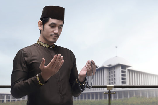 Portrait of asian muslim man raising hand and praying