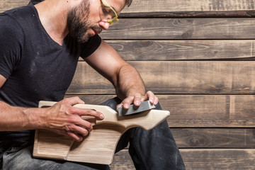 Young man builder carpenter handles a wooden board in the workshop, half-tree wood