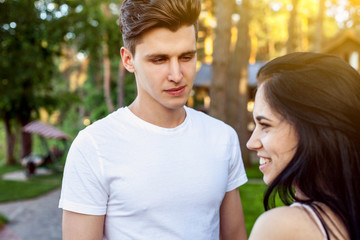 Obraz premium Beautiful young couple during a romantic date. The guy seriously looking at his beloved laughing girl with the perfect smile on a Sunny day