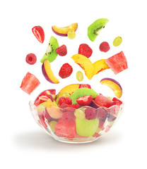 Fruit salad fall into glass bowl isolated on white